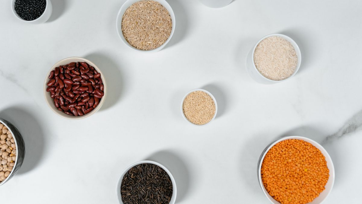 Overhead view of bowls holding dry beans, lentils, rice, and other grains