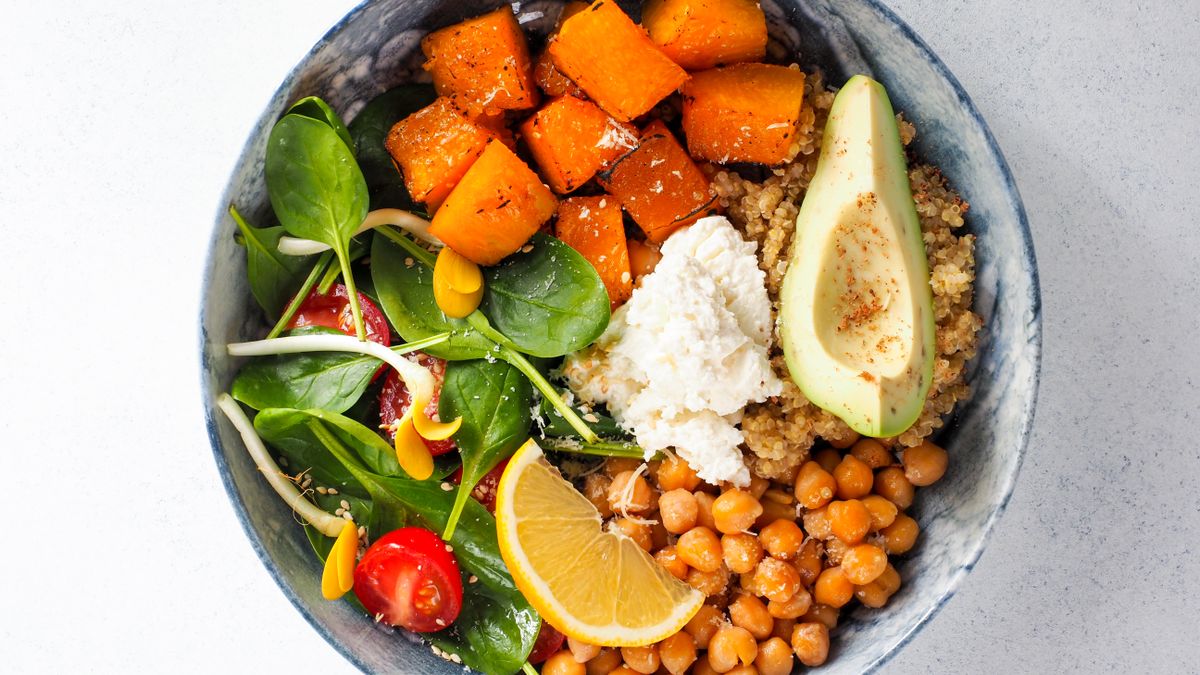 Overhead view of a quinoa bowl with chickpeas, roasted sweet potato, avocado, and spinach